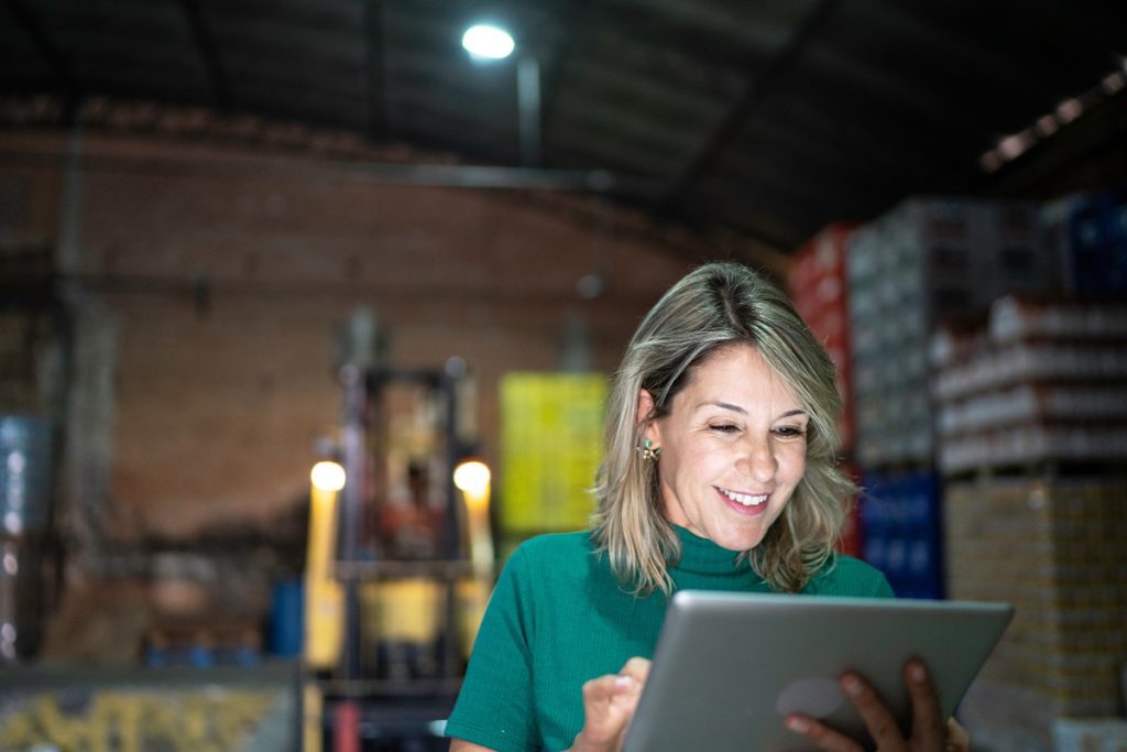 Smiling employee using digital tablet in warehouse
