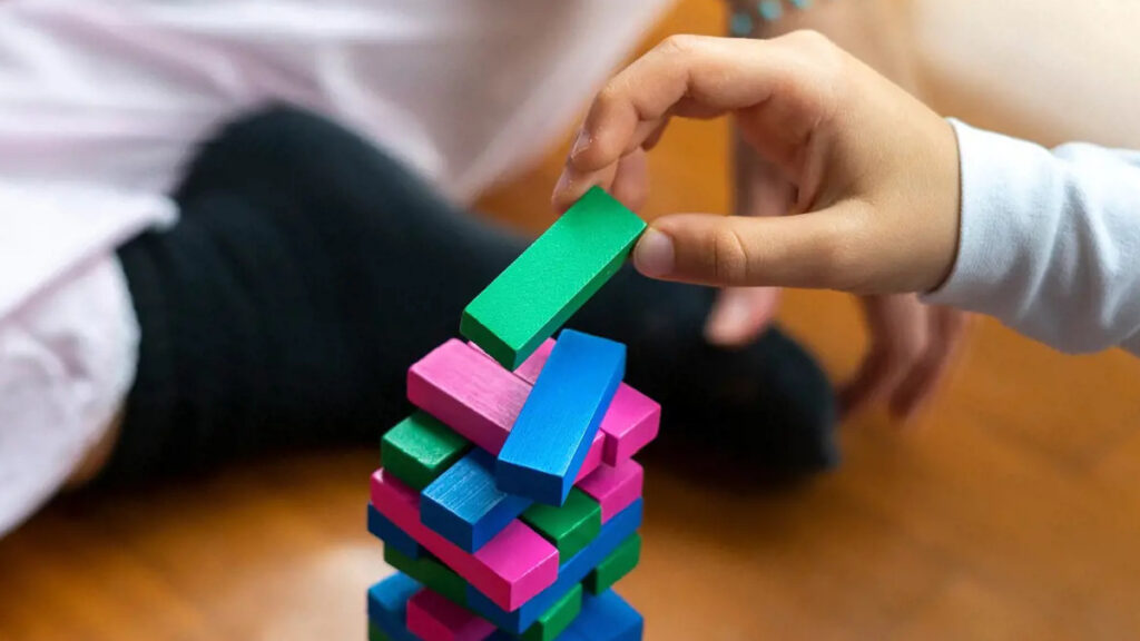 Child playing with a colorful stack of building blocks, symbolizing the building and implementation of AI solutions for non-profits.