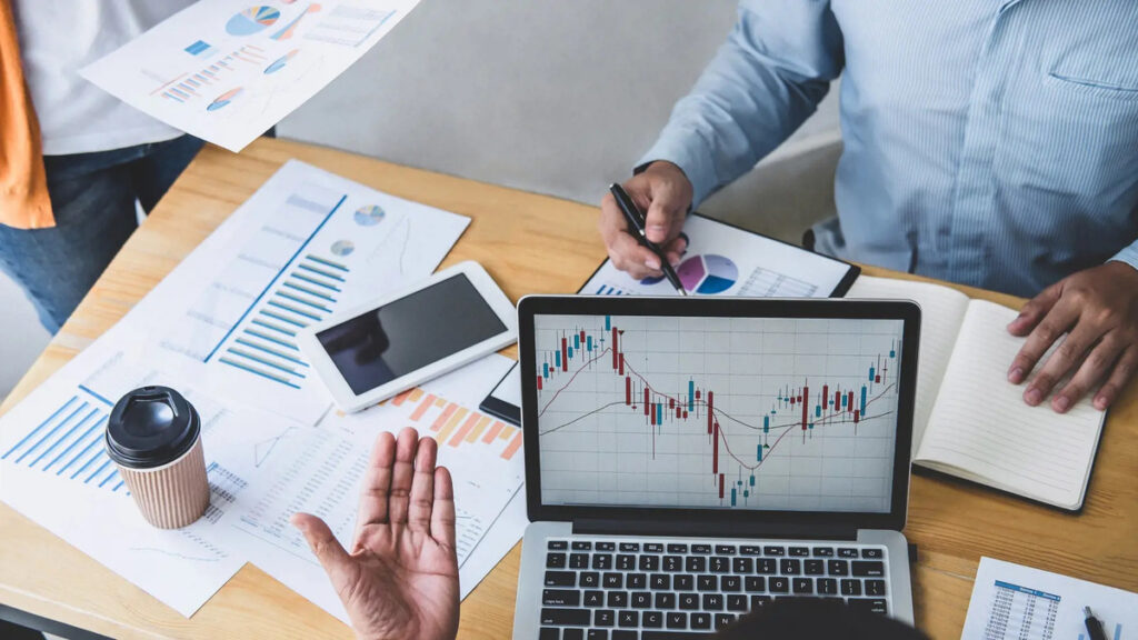 Team analyzing financial data on a laptop and printed charts, using Microsoft Dynamics 365 for State and Local Governments for efficient fiscal management.